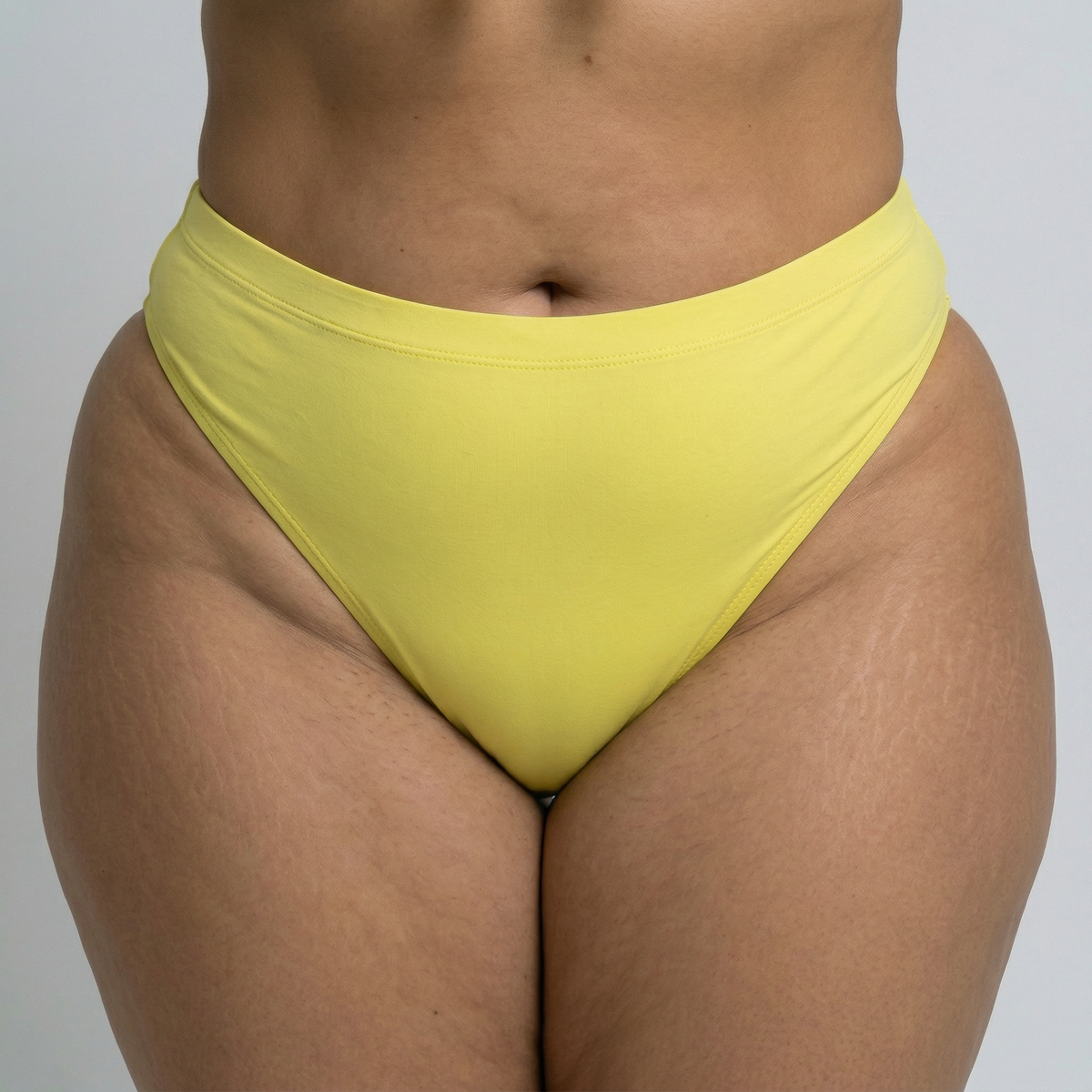 Close-up of Lemon Drop plus size bikini bottom in bright yellow on curvy model in studio