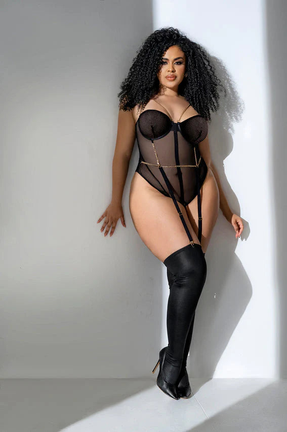 Plus size model wearing black sheer mesh and fishnet bodysuit with underwire cups, chain details, and garter straps front view