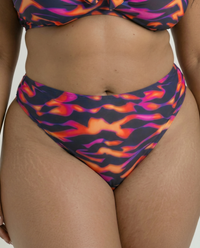 Close-up of Purple Blaze plus size bikini bottom with vibrant abstract flame print on curvy model in studio