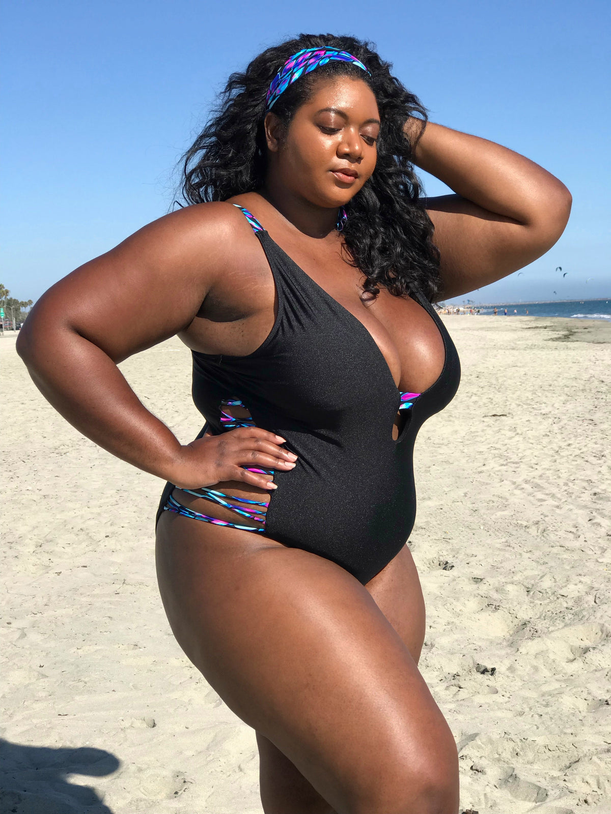 Plus-size model wearing Black Oasis Plunging One-Piece Swimsuit, designed to enhance curves and offer confidence.