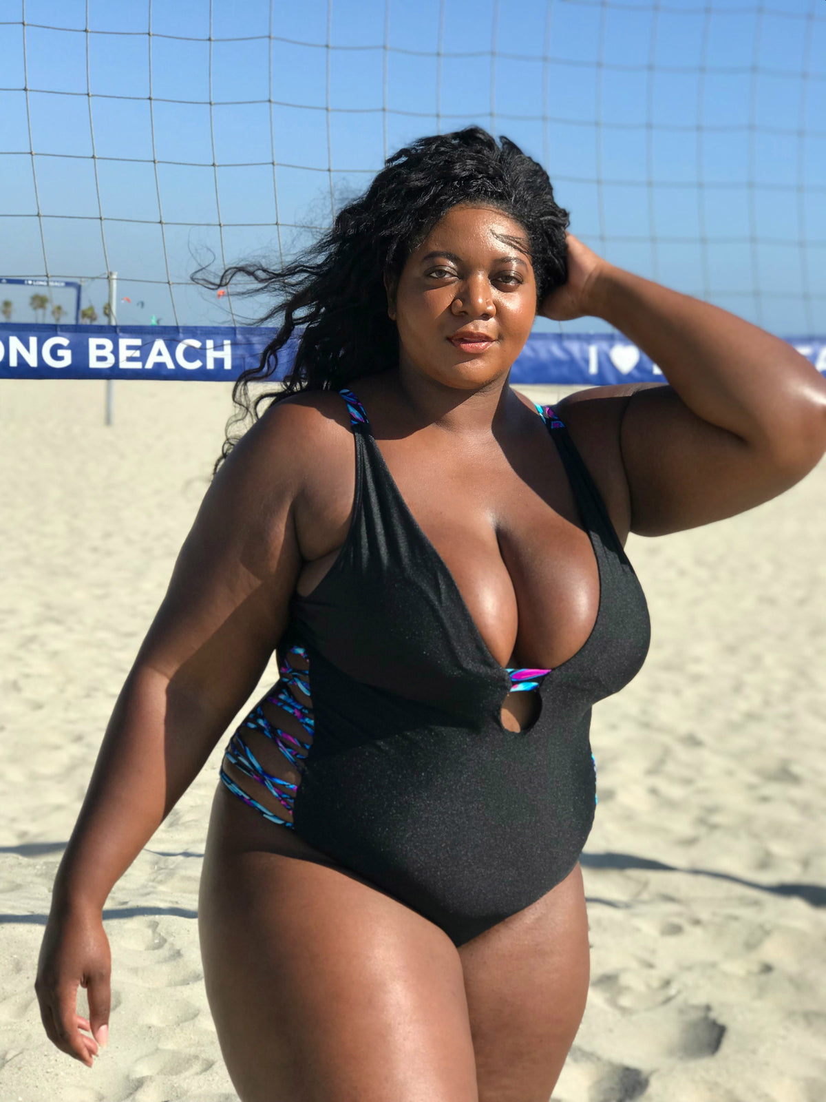 Plus-size model wearing Black Oasis Plunging One-Piece Swimsuit, designed to enhance curves and offer comfort and support.